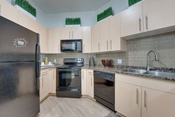 A kitchen with a black refrigerator and wooden floors.